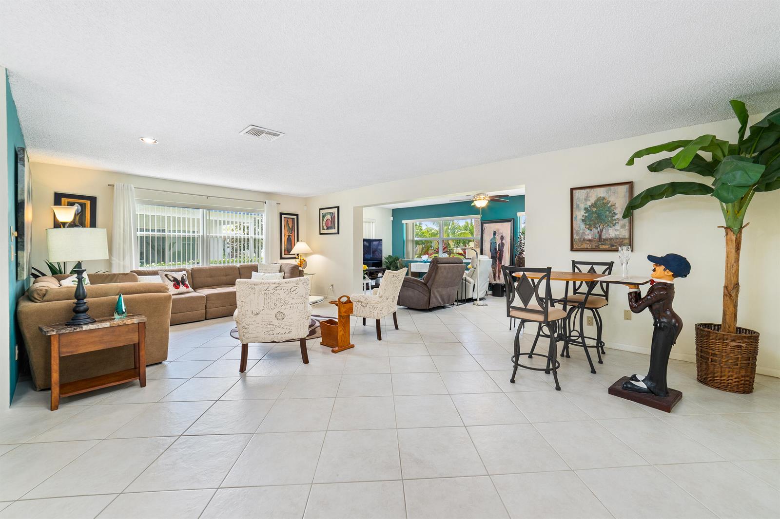 A spacious living and dining area features light tile flooring, neutral walls, and a sectional sofa — 6303 Silver Moon Lane, FL 33463, FL