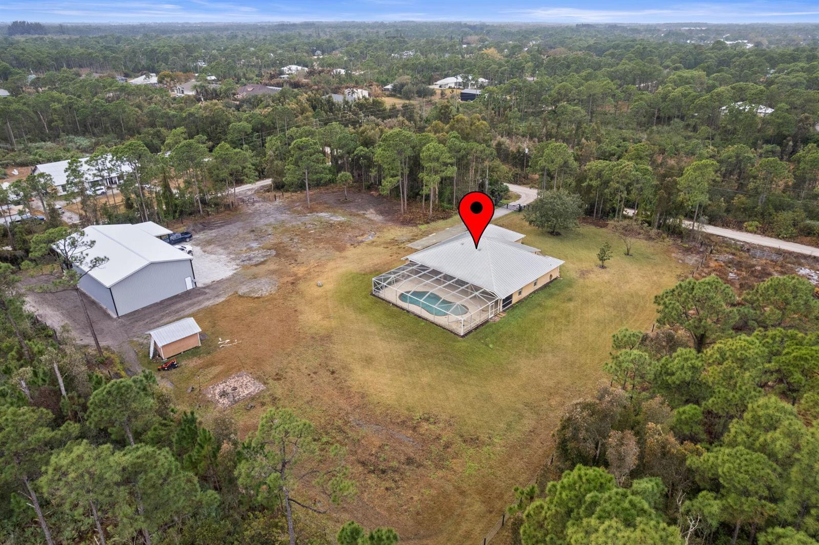 An aerial view shows a house with a screened pool, a detached garage, and surrounding woods — 5224 Southwind Trail, Fort Pierce FL 34951, FORT PIERCE, FL