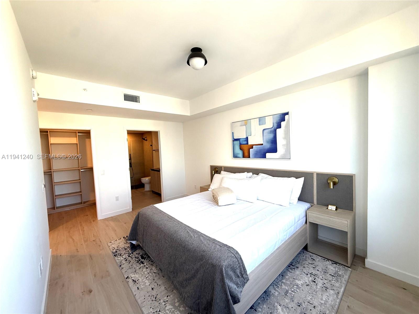 A bedroom features a bed with a gray throw, a walk-in closet, and an attached bathroom — 225 N MIAMI AVE # 3505, Miami FL 33132, MIAMI, FL