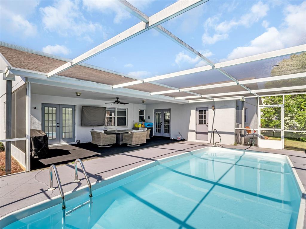 A screened-in patio features a swimming pool, outdoor furniture, and multiple sets of glass doors — 13635 MUFFIN COURT, HUDSON, FL