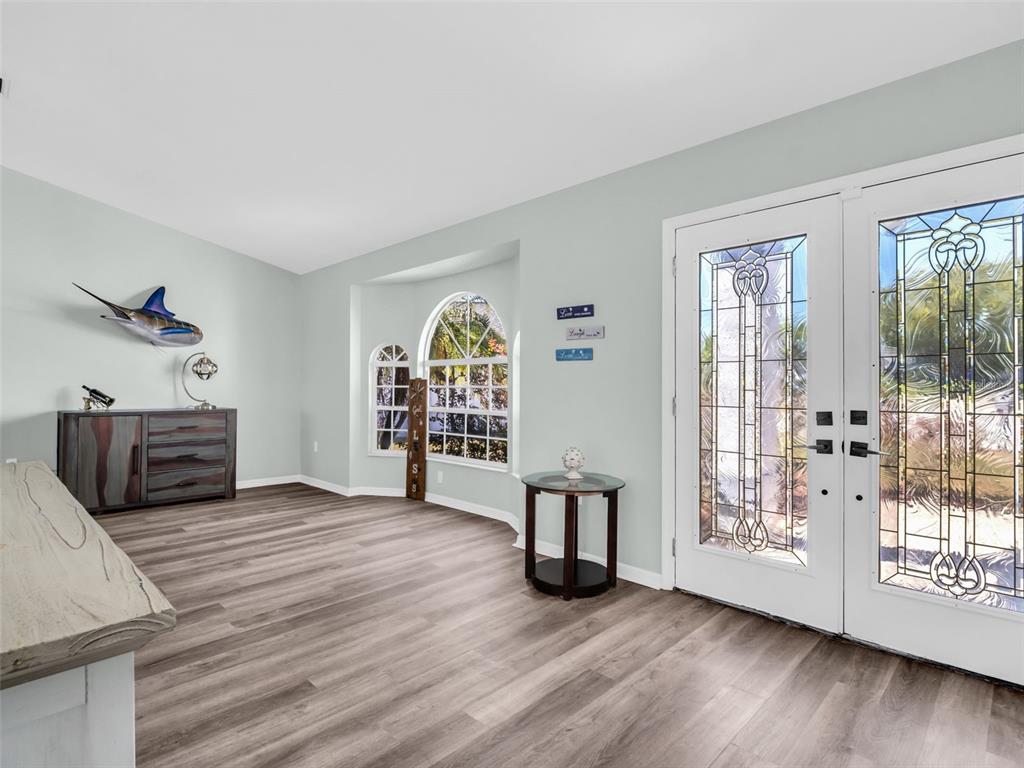 An entryway features wood-look flooring, a double glass door, and a decorative fish wall mount — 13635 MUFFIN COURT, HUDSON, FL