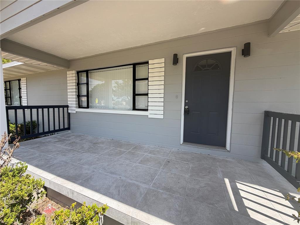 A gray house exterior features a tiled front porch, a dark door, and large windows — 131 W ATWATER AVENUE, EUSTIS, FL