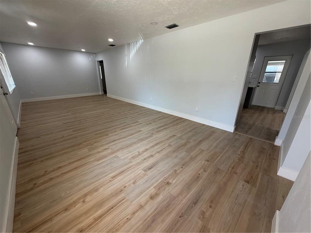 An empty room with light wood-look flooring, white walls, and recessed ceiling lighting — 131 W ATWATER AVENUE, EUSTIS, FL