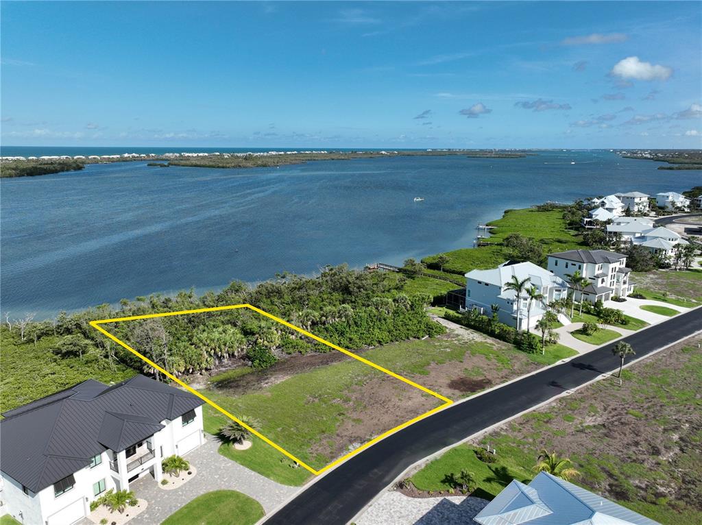 An aerial view shows a vacant waterfront lot outlined in yellow next to residential homes — 10011 EAGLE PRESERVE DRIVE, ENGLEWOOD, FL