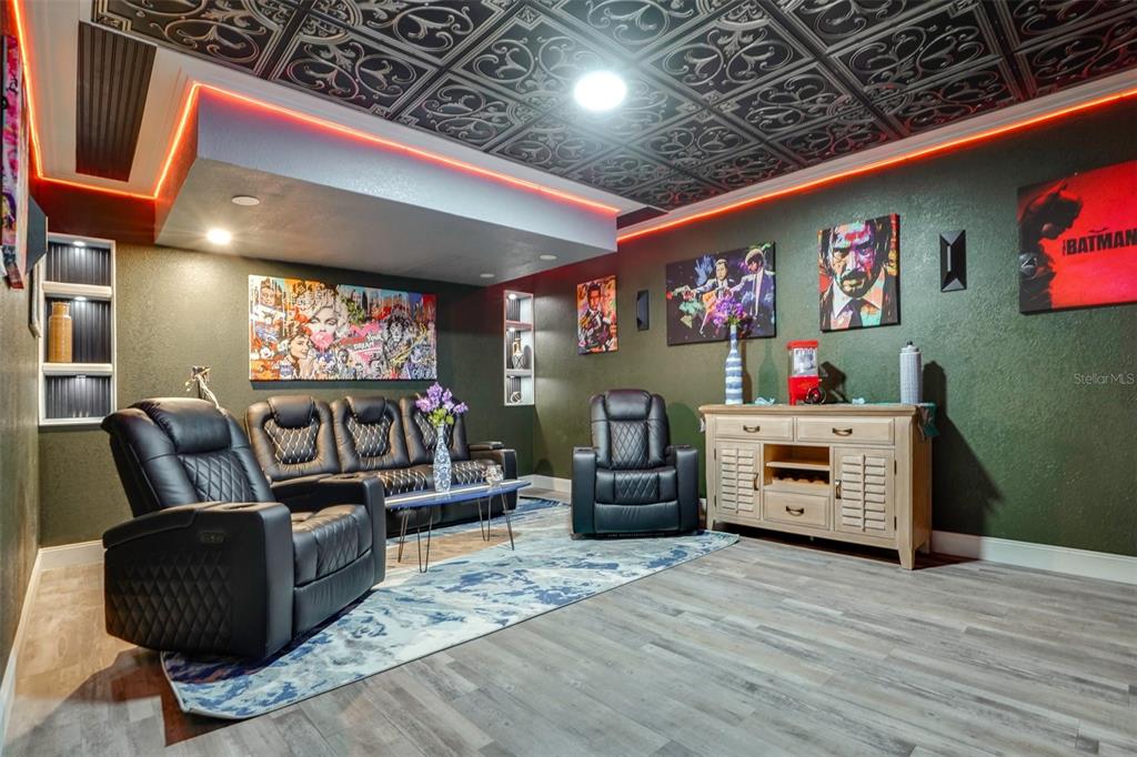 A home theater room with black leather recliners, a patterned ceiling, and movie-themed wall art — 2741 PARMA STREET, SARASOTA, FL