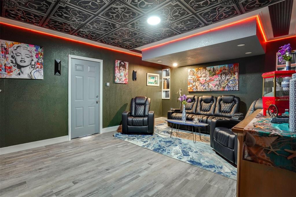 A basement media room features dark walls, a patterned ceiling, red accent lighting, and leather seating — 2741 PARMA STREET, SARASOTA, FL