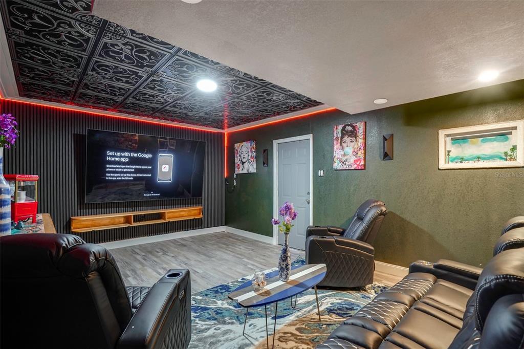 A home theater room features a black paneled accent wall, patterned ceiling tiles, and leather seating — 2741 PARMA STREET, SARASOTA, FL
