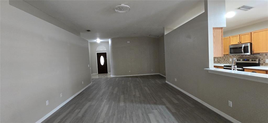 An open-concept living area features gray walls, wood-look flooring, and a kitchen with wooden cabinets — 1810 GREYSTONE HEIGHTS DRIVE, VALRICO, FL