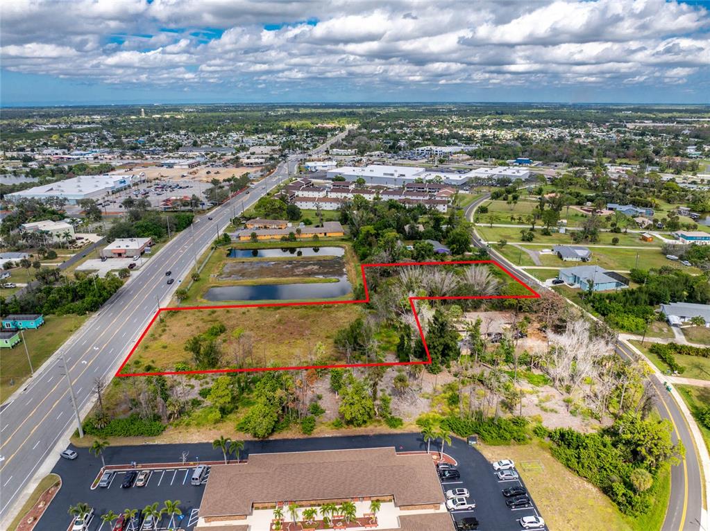An aerial view shows a vacant, rectangular lot outlined in red next to a road — 1701 PLACIDA ROAD, ENGLEWOOD, FL