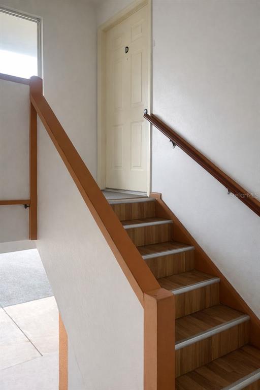 A staircase with wood-look treads leads to a white door labeled D — 1817 MICHIGAN AVENUE UNIT D, KISSIMMEE, FL