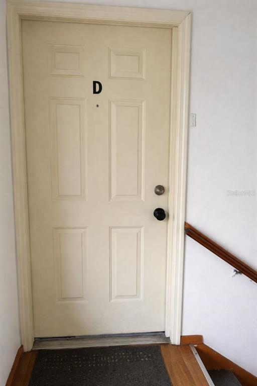 A white six-panel door labeled with the letter D sits at the top of stairs — 1817 MICHIGAN AVENUE UNIT D, KISSIMMEE, FL