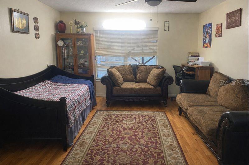 A living room features a daybed, a loveseat, a sofa, and a desk on wood flooring — 1817 MICHIGAN AVENUE UNIT D, KISSIMMEE, FL