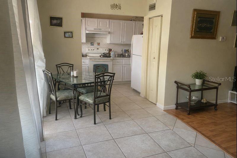 A dining area with a glass table and chairs sits adjacent to a white kitchen — 1817 MICHIGAN AVENUE UNIT D, KISSIMMEE, FL