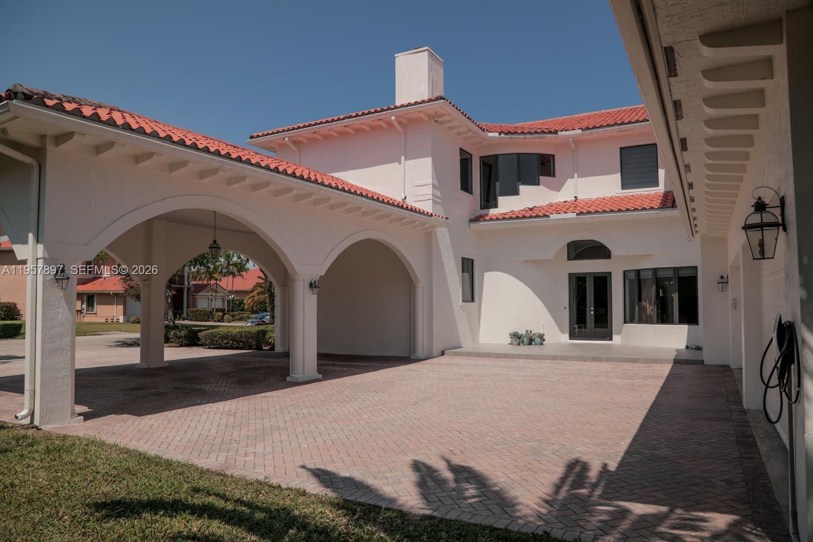 A white stucco house features a red tile roof, arched porte-cochère, and brick driveway — 19209 SW 80th Ct, Cutler Bay FL 33157, CUTLER BAY, FL