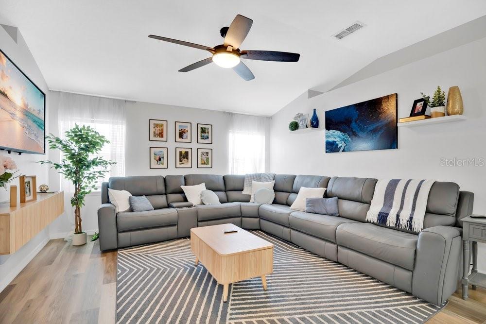 A living room features a large gray sectional sofa, a coffee table, and a ceiling fan — 213 BRUSHCREEK DRIVE, SANFORD, FL