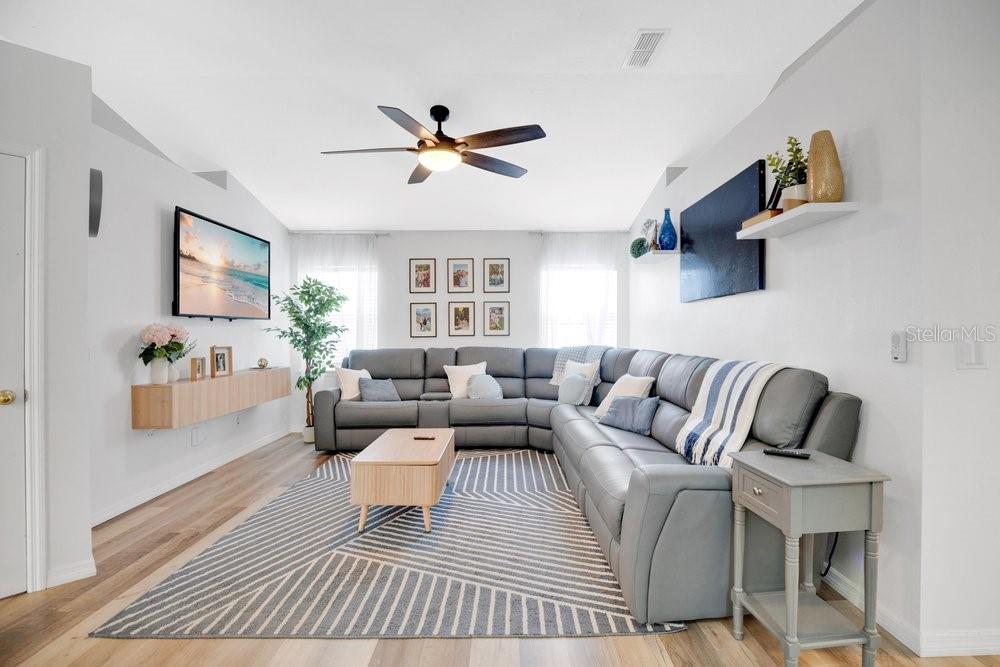 A living room features a large gray sectional sofa, a patterned rug, and a ceiling fan — 213 BRUSHCREEK DRIVE, SANFORD, FL