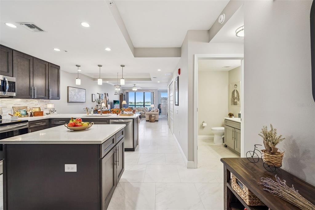 A modern kitchen with dark cabinets and a white island opens to a living area — 16300 COUNTY ROAD 455 UNIT 503, MONTVERDE, FL