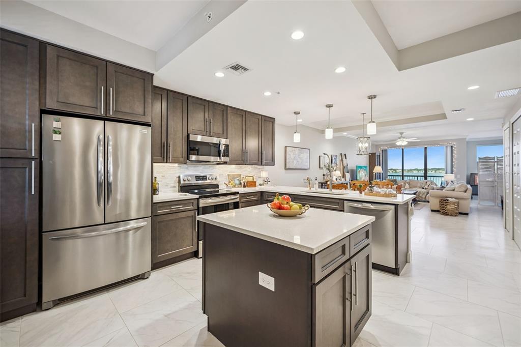 A modern kitchen features dark wood cabinets, stainless steel appliances, and a central island — 16300 COUNTY ROAD 455 UNIT 503, MONTVERDE, FL