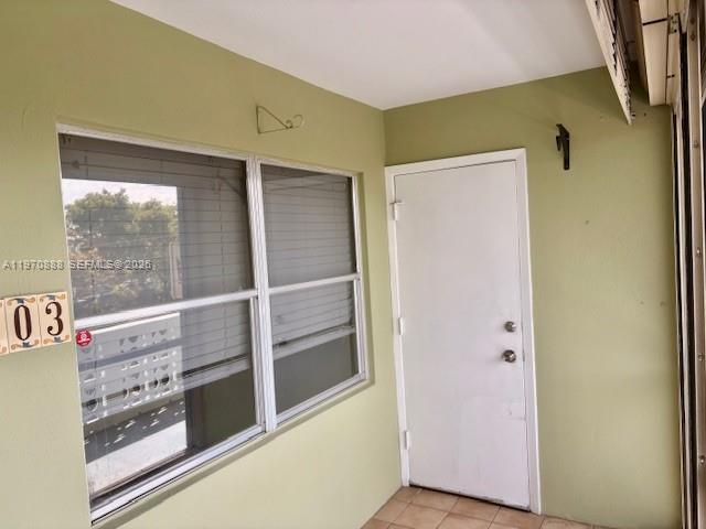 A light green enclosed balcony features a large window with blinds and a white door — 1425 Arthur St # 403A, Hollywood FL 33020, HOLLYWOOD, FL