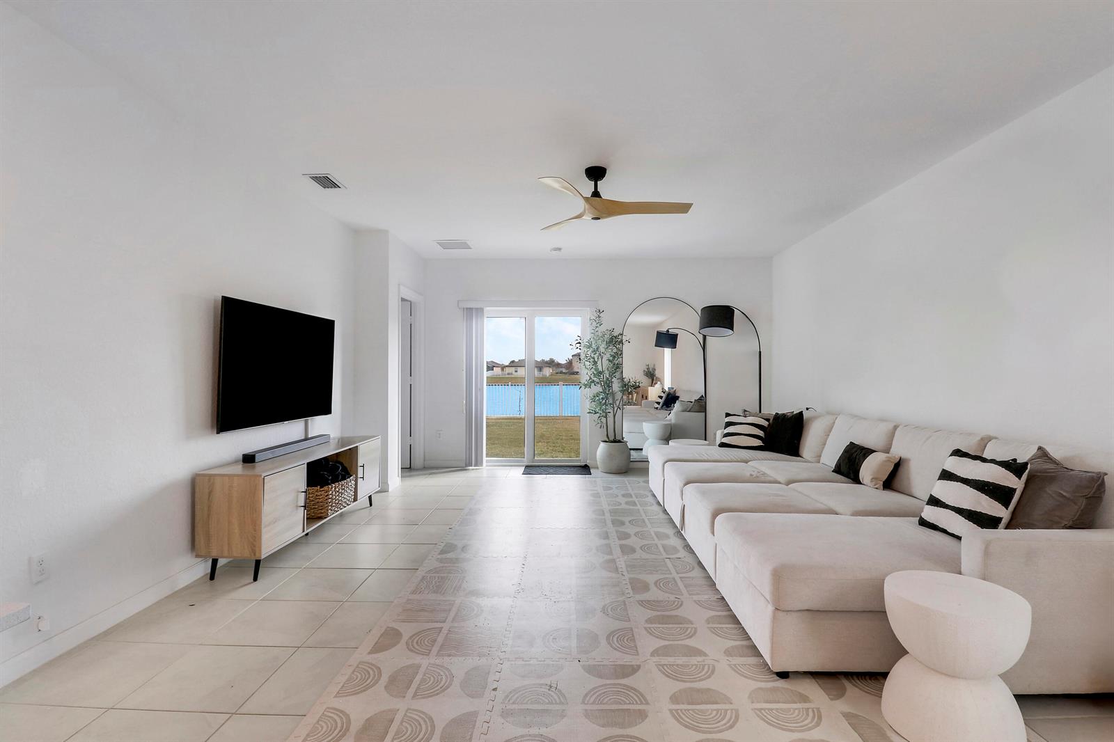 A living room features a large sectional sofa, a television console, and sliding glass doors — 4233 Troon Place, Fort Pierce FL 34947, FORT PIERCE, FL