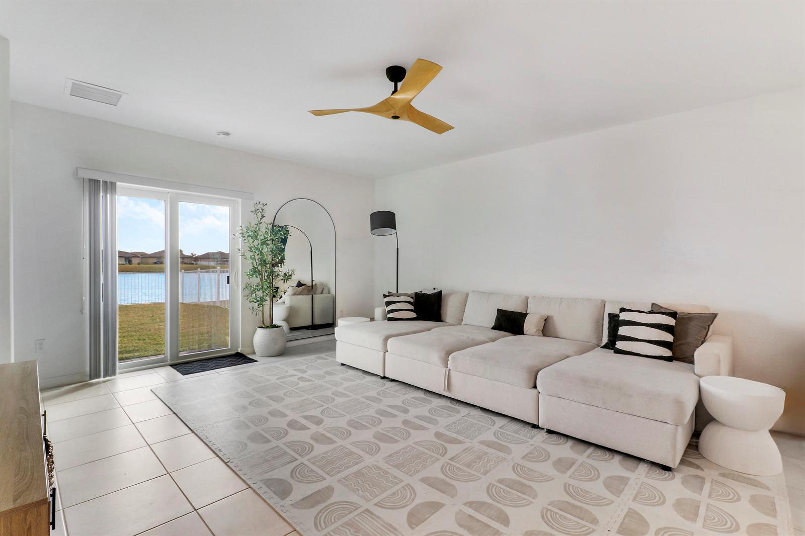 A living room features a large sectional sofa, patterned area rug, ceiling fan, and sliding doors — 4233 Troon Place, Fort Pierce FL 34947, FORT PIERCE, FL