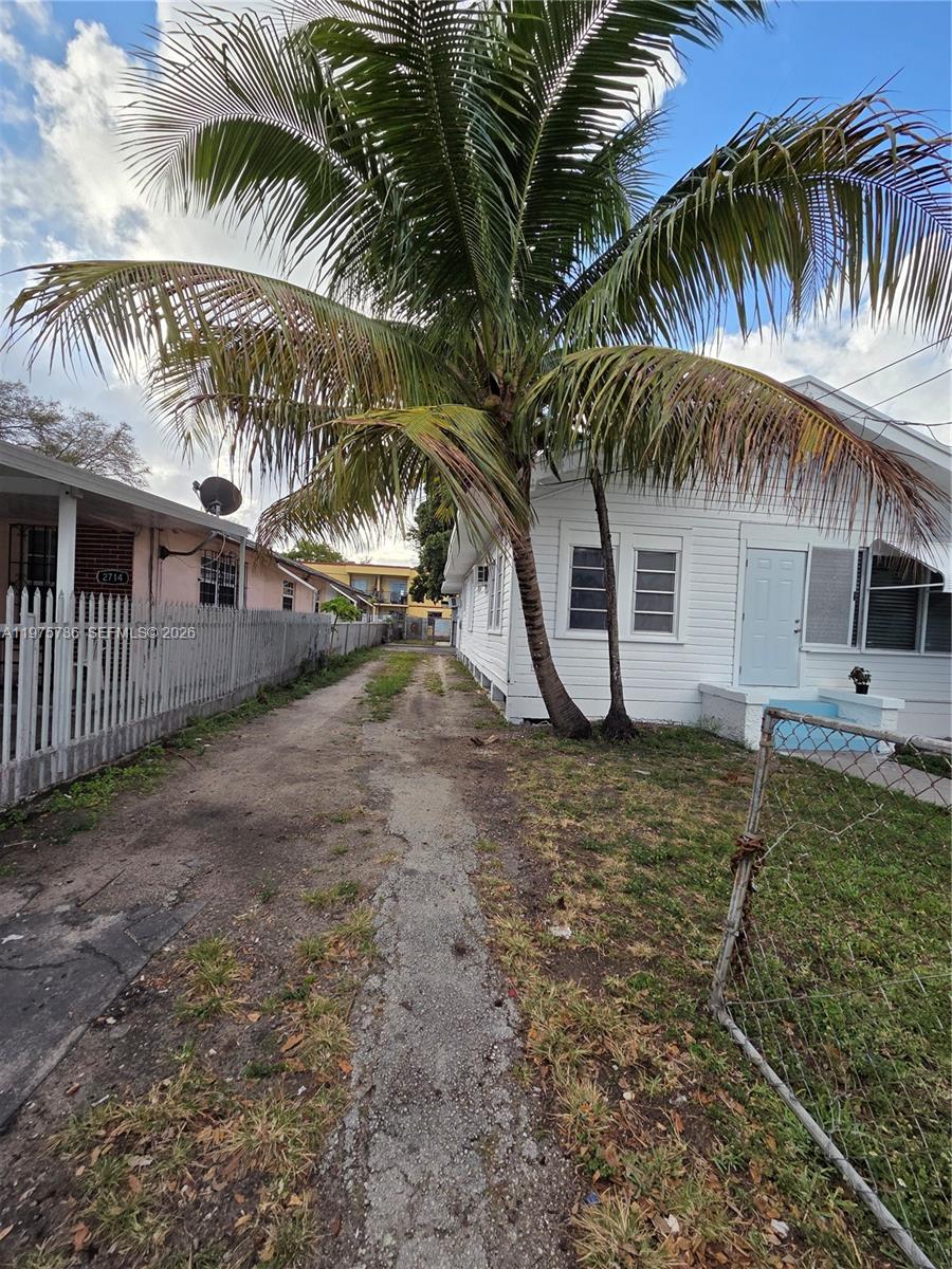 A dirt driveway leads between a white house and a fenced pink house — 2722 NW 23rd Ave, Miami FL 33142, MIAMI, FL