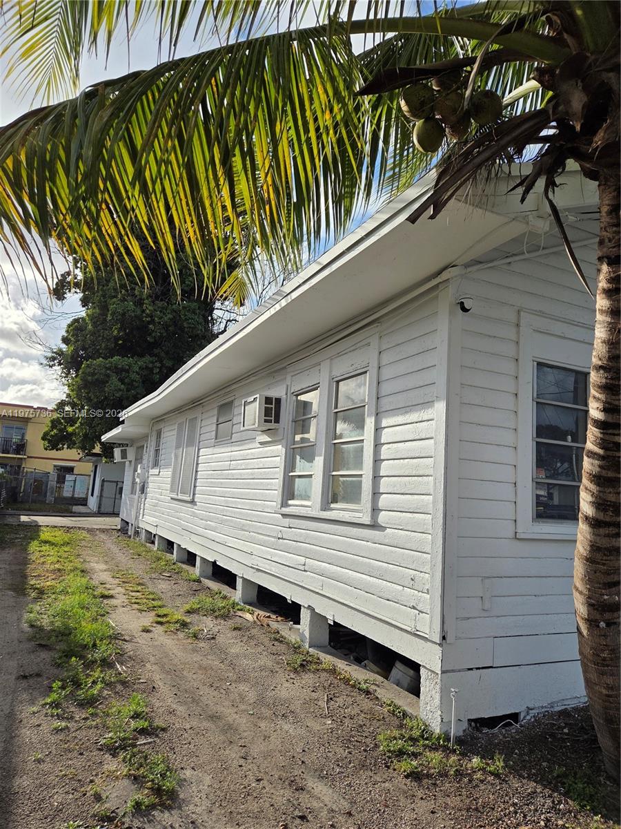 A white, wood-sided house with a pier-and-beam foundation stands next to a palm tree — 2722 NW 23rd Ave, Miami FL 33142, MIAMI, FL