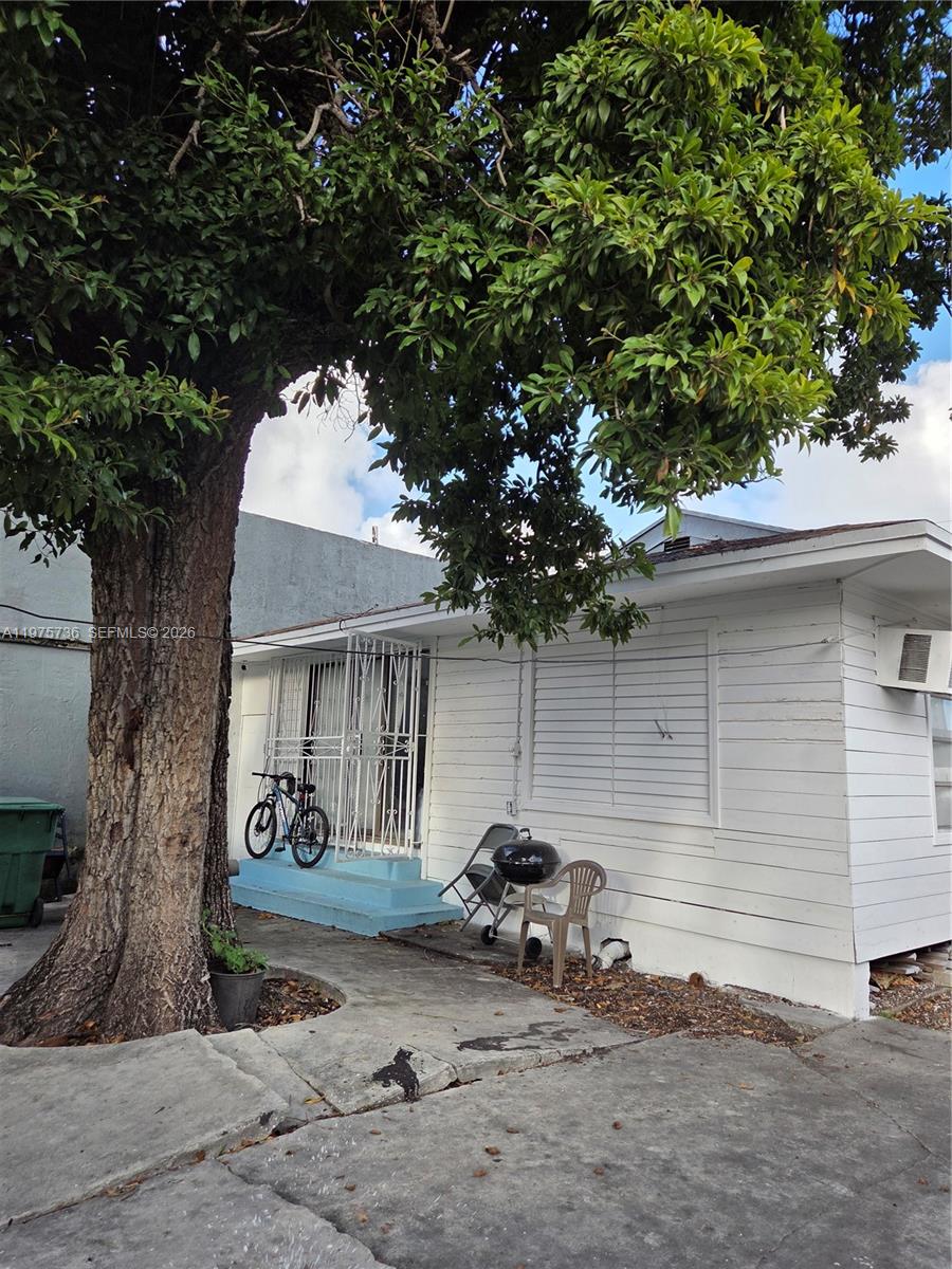 A white house with a large tree in front and a bicycle on the porch — 2722 NW 23rd Ave, Miami FL 33142, MIAMI, FL