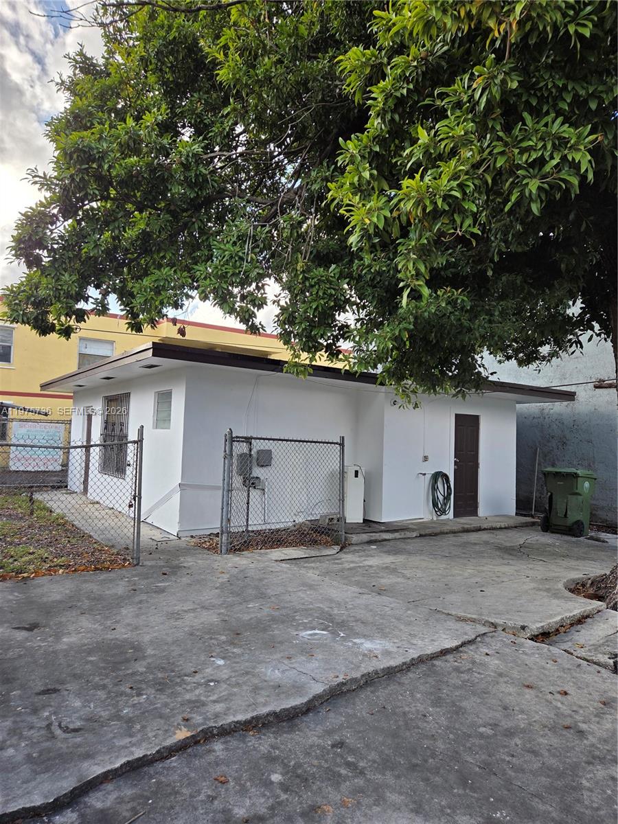 A white, single-story building with a flat roof sits behind a chain-link fence — 2722 NW 23rd Ave, Miami FL 33142, MIAMI, FL