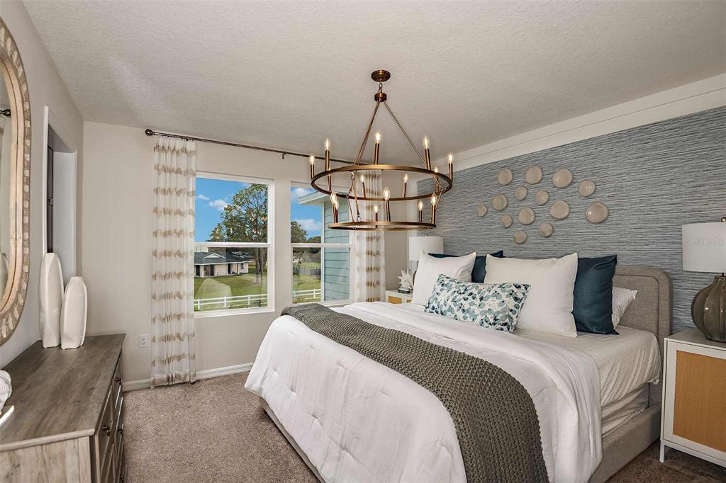 A bedroom features a bed with white bedding, a chandelier, and a textured blue accent wall — 4254 HILLOCK BOULEVARD, HAINES CITY, FL