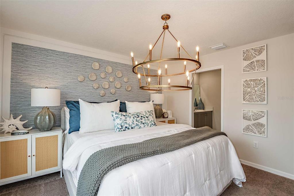 A bedroom features a textured blue accent wall, a chandelier, and a white bed — 4254 HILLOCK BOULEVARD, HAINES CITY, FL