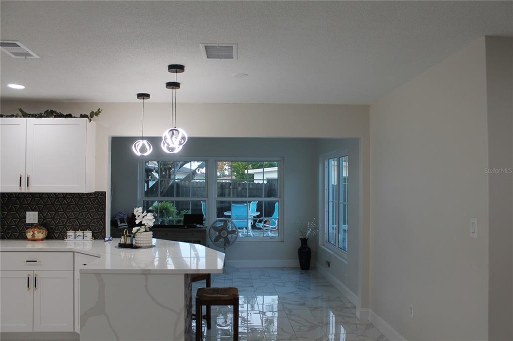A kitchen with a white island, pendant lighting, and a dining area with large windows — 7423 STAR DUST DRIVE, PORT RICHEY, FL
