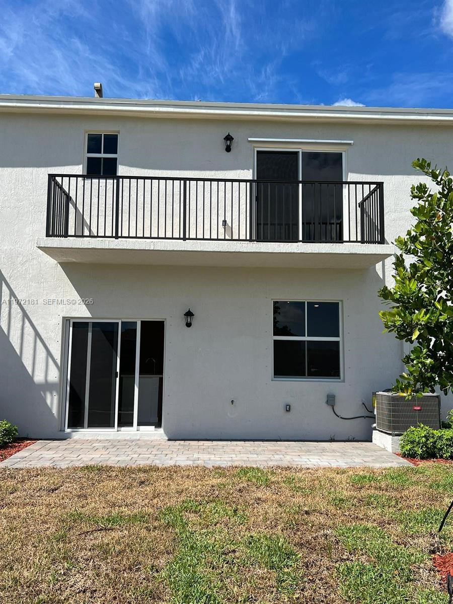 The exterior of a two-story building features a balcony, sliding glass doors, and a patio — 1765 SE 7th Ter, Homestead FL 33034, HOMESTEAD, FL
