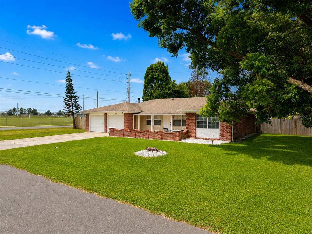 A single-story brick house with a two-car garage and a front lawn under a tree — 1594 FRANCES STREET, KISSIMMEE, FL