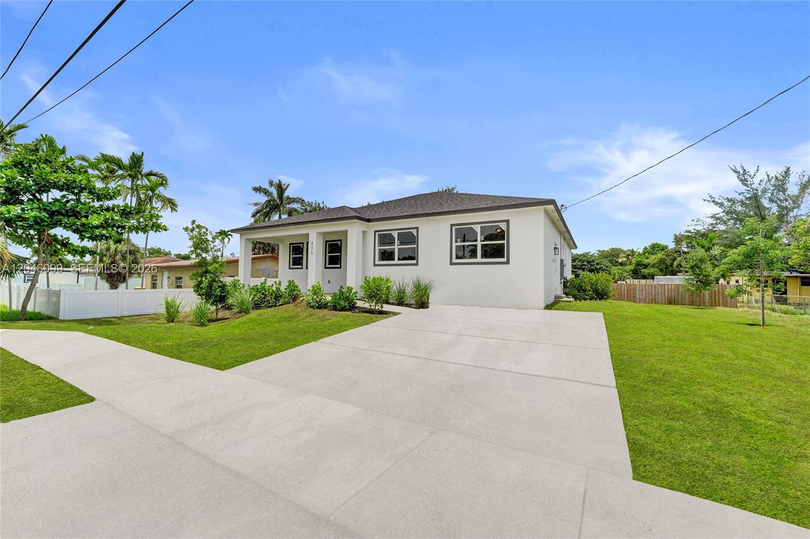 A white single-story house features a concrete driveway and a small front lawn — 211 NW 14th Ct, Dania Beach FL 33004, DANIA BEACH, FL