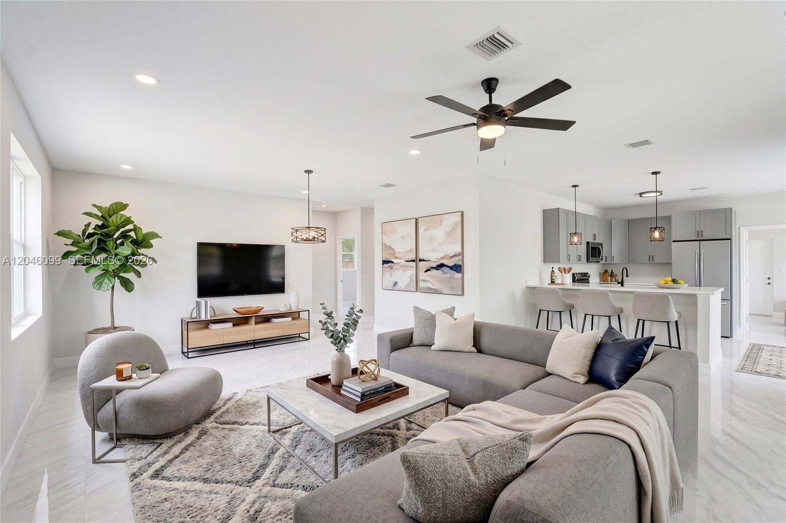 A modern open-concept living room features a grey sectional, marble coffee table, and kitchen island — 211 NW 14th Ct, Dania Beach FL 33004, DANIA BEACH, FL