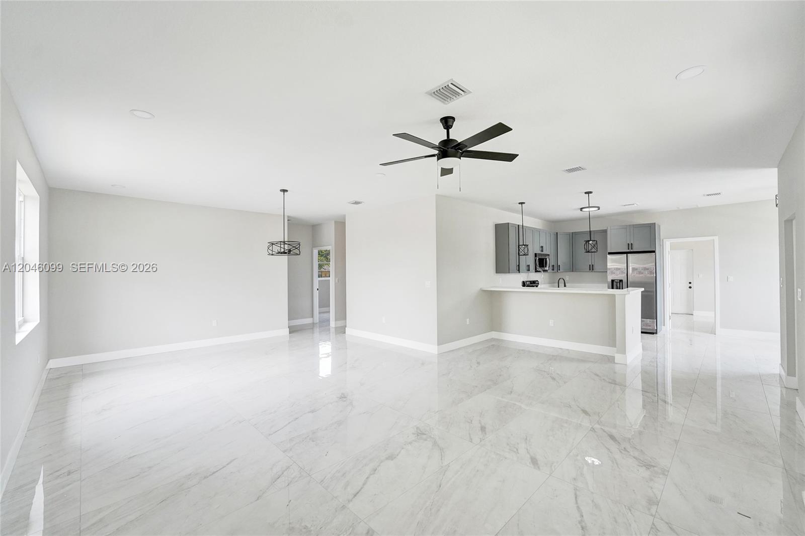 A bright, open-concept kitchen and living area features white marble-look tile flooring and neutral walls — 211 NW 14th Ct, Dania Beach FL 33004, DANIA BEACH, FL