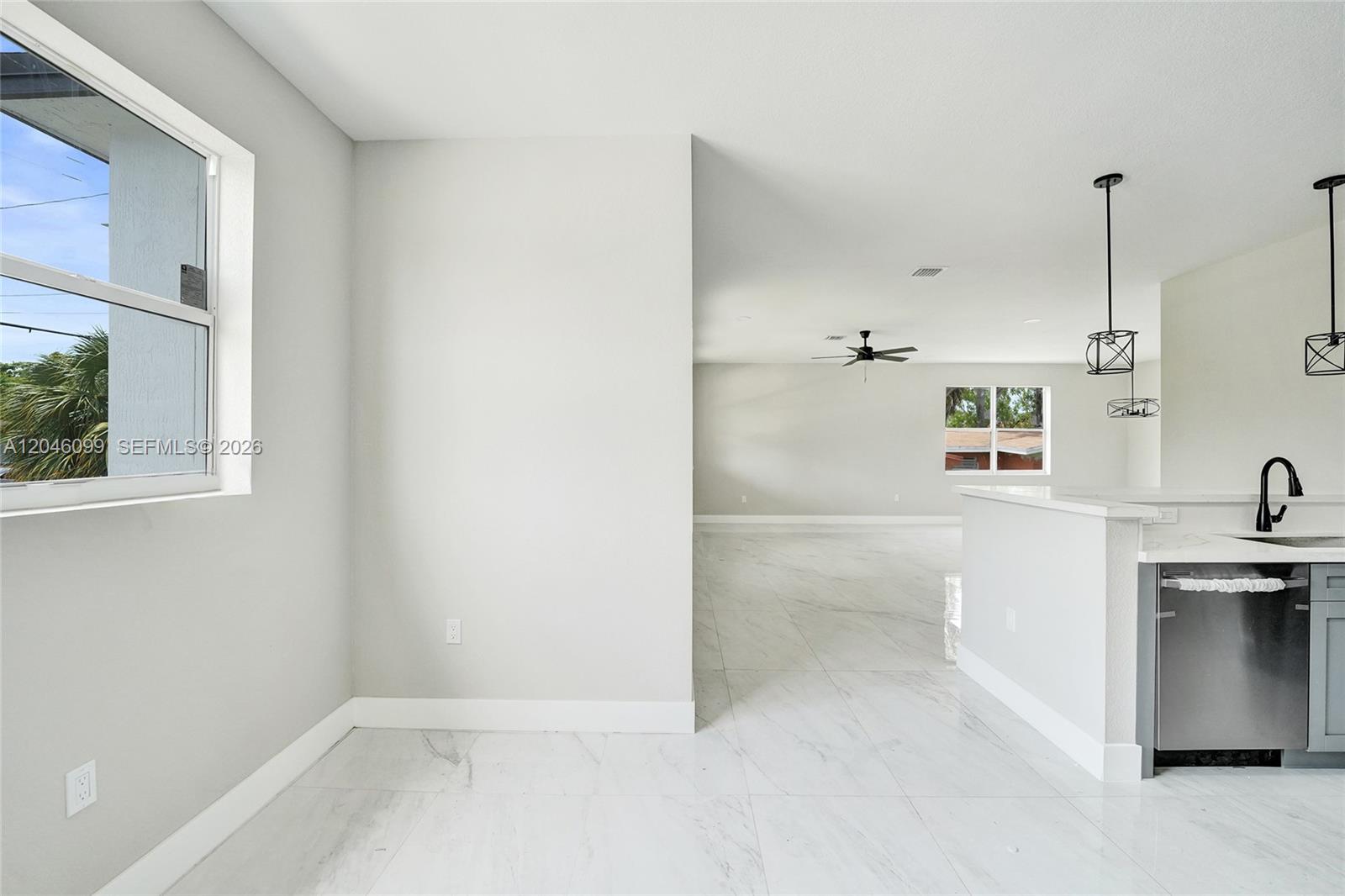 A modern kitchen features gray cabinets, stainless steel appliances, and white marble-style tile flooring — 211 NW 14th Ct, Dania Beach FL 33004, DANIA BEACH, FL