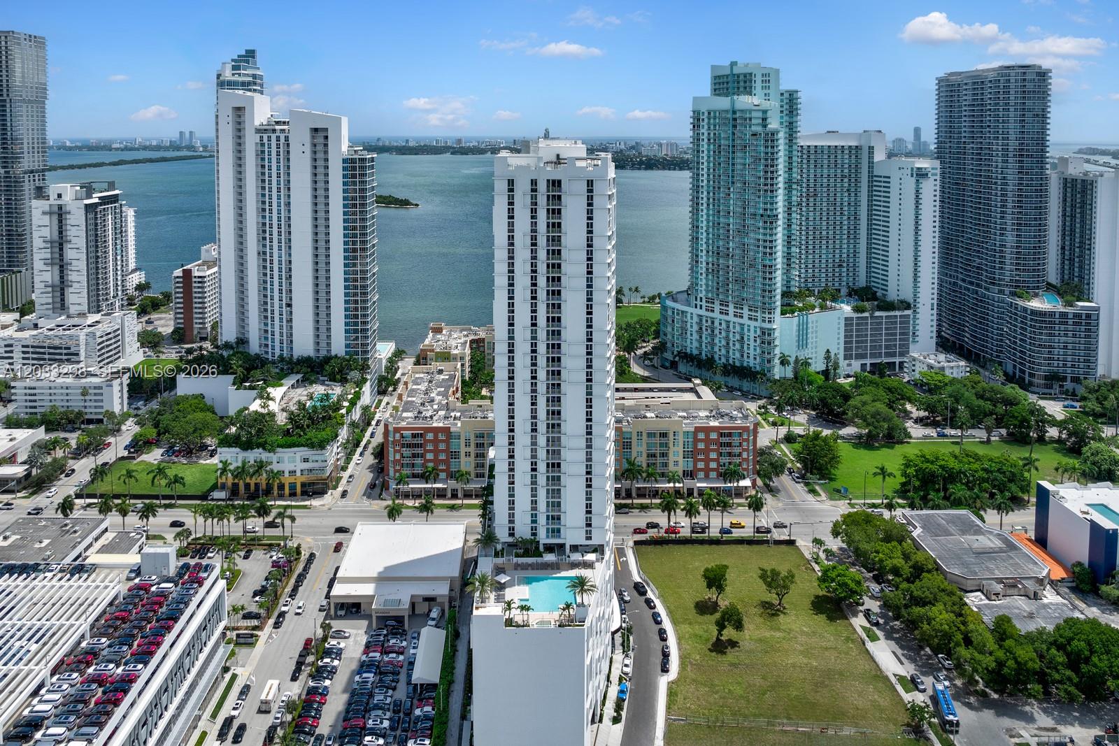 An aerial view of a tall white residential building in a dense urban waterfront area — 2000 Biscayne Blvd # 1009, Miami FL 33137, MIAMI, FL