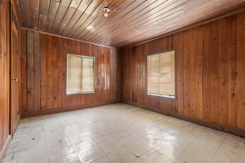 An empty room features wood-paneled walls, a wood-plank ceiling, and light-colored square floor tiles — 2413 ED BROWN LANE, PLANT CITY, FL
