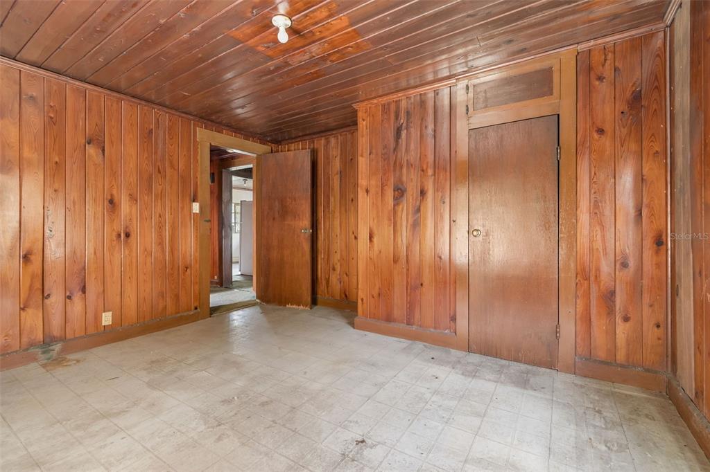 A room with wood-paneled walls and ceiling, a tiled floor, and two wooden doors — 2413 ED BROWN LANE, PLANT CITY, FL