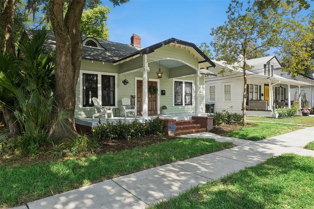 A light green bungalow with a front porch, dark window frames, and a brick foundation — 12 N THORNTON AVENUE, ORLANDO, FL