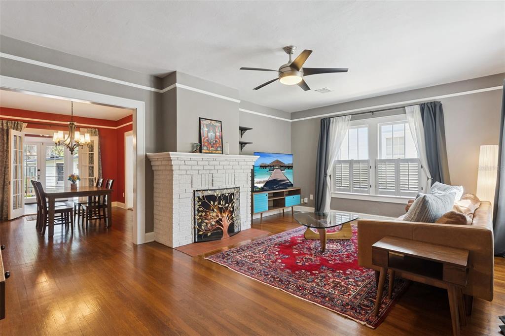 A living room with a white brick fireplace, hardwood floors, and an adjacent dining area — 12 N THORNTON AVENUE, ORLANDO, FL