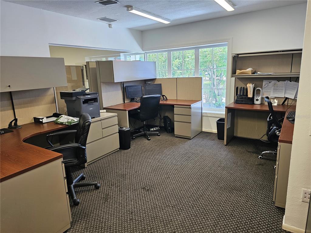 An office space features three modular desks with chairs, computers, and large windows — 28960 US HIGHWAY 19 N UNIT 102, CLEARWATER, FL