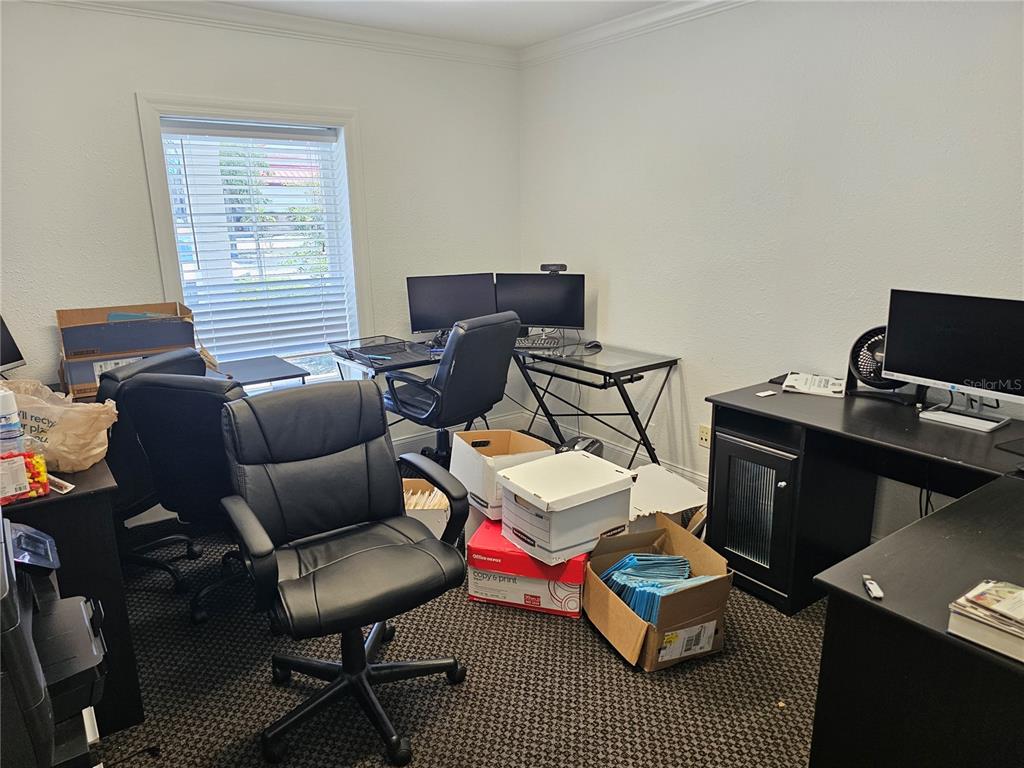 A home office features two desks, multiple computer monitors, office chairs, and stacked storage boxes — 28960 US HIGHWAY 19 N UNIT 102, CLEARWATER, FL