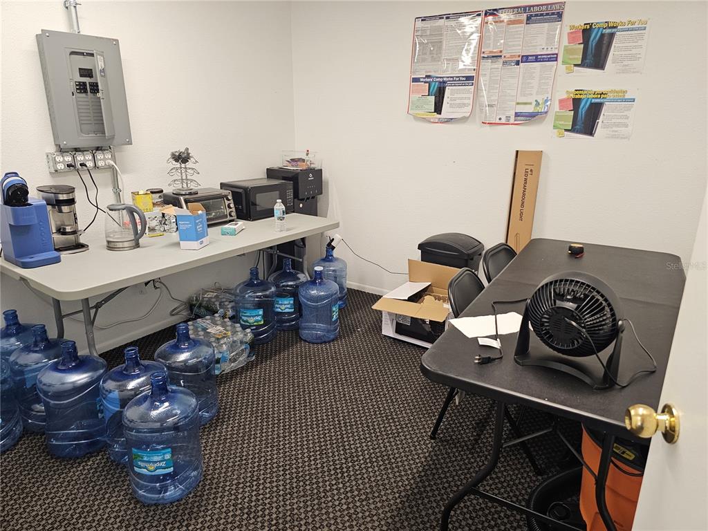 A break room features a folding table with kitchen appliances, water jugs, and a desk fan — 28960 US HIGHWAY 19 N UNIT 102, CLEARWATER, FL