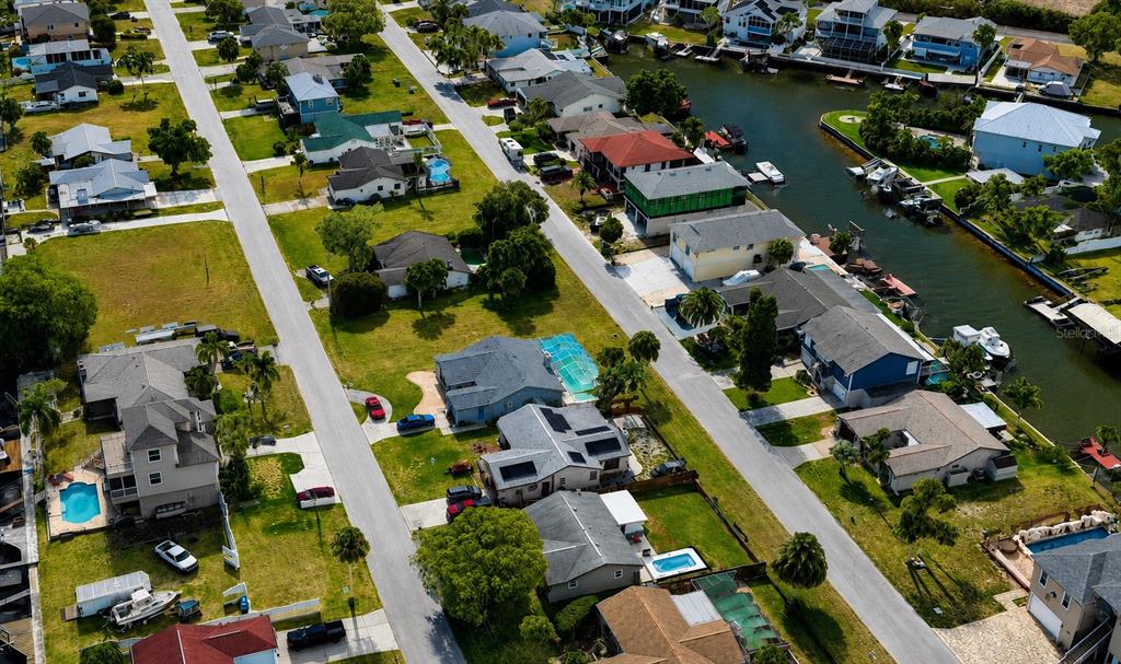 An aerial view shows suburban homes with swimming pools and boat docks along a canal — 7505 MAKO DRIVE, HUDSON, FL