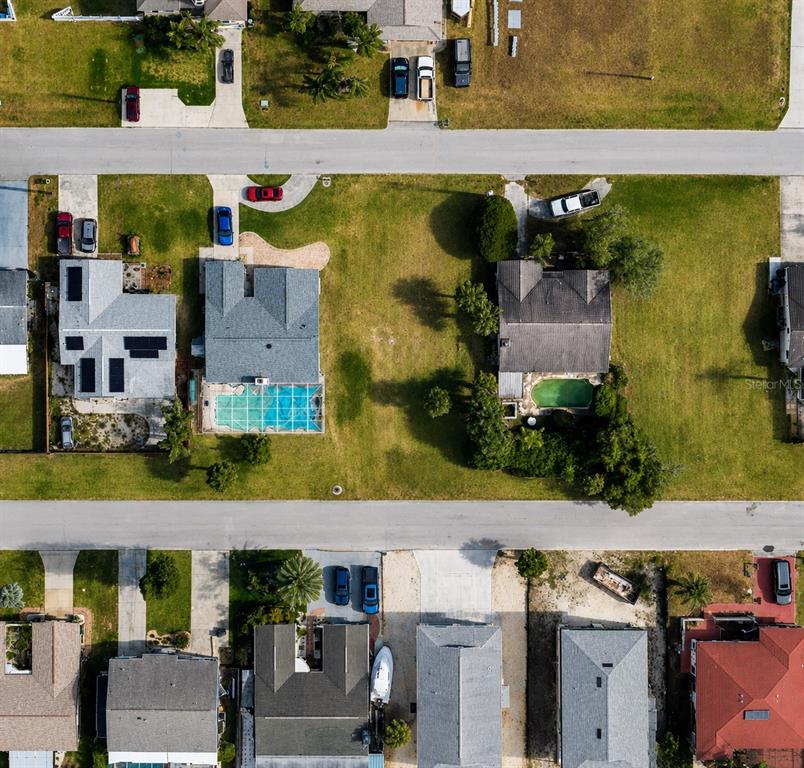 An aerial view shows several residential houses with swimming pools and driveways along two streets — 7505 MAKO DRIVE, HUDSON, FL