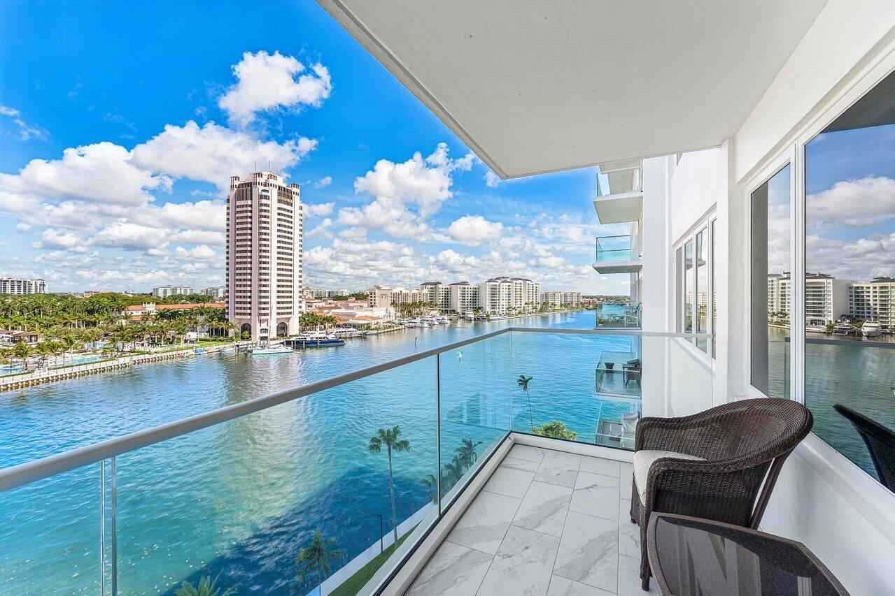 A balcony with a glass railing overlooks a waterway, a tall building, and distant structures — 701 E Camino Real Apt 9g, Boca Raton FL 33432, BOCA RATON, FL