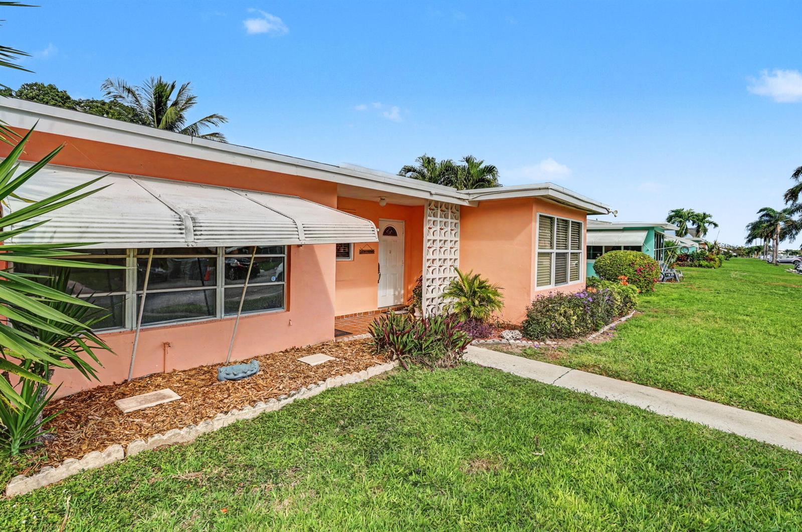 A peach-colored single-story house features a metal awning, decorative concrete blocks, and a lawn — 275 South Boulevard # C, Boynton Beach FL 33435, BOYNTON BEACH, FL